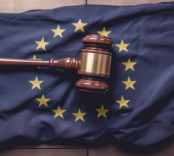 Ein Richterhammer liegt auf einer EU-Flagge, symbolisierend die Verabschiedung der KI-Gesetzgebung durch die Europäische Union.