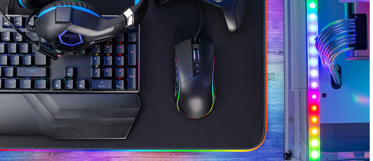 Ein Gaming-Setup mit RGB-Beleuchtung, bestehend aus einer Tastatur, Maus, Headset und LED-Streifen, das eine farbenfrohe und moderne Atmosphäre schafft.