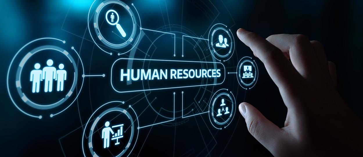 Das Bild zeigt eine Hand, die auf ein futuristisches Interface tippt, welches verschiedene Symbole und den Schriftzug "HUMAN RESOURCES" anzeigt und damit auf digitale Technologien im Personalwesen hinweist.