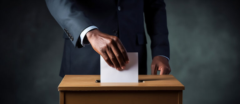 Das Foto zeigt eine Person, die ihren Wahlbrief in eine Urne wirfr.