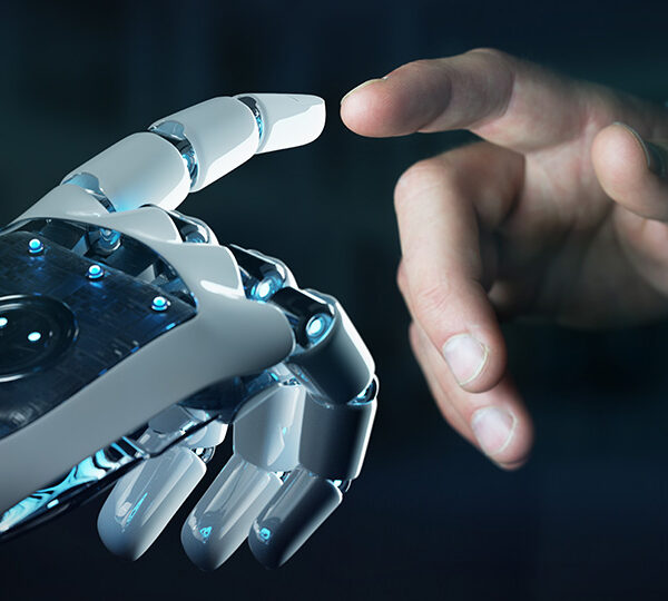 Das Bild zeigt eine menschliche Hand, die sich einer Roboterhand nähert, was die Verbindung und Interaktion zwischen Mensch und Technologie symbolisiert.