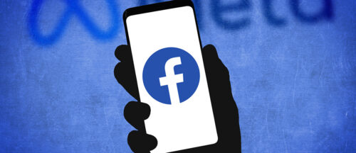 Eine Person hat ein Smartphone in der Hand, wo das Facebook-Logo zu sehen ist.