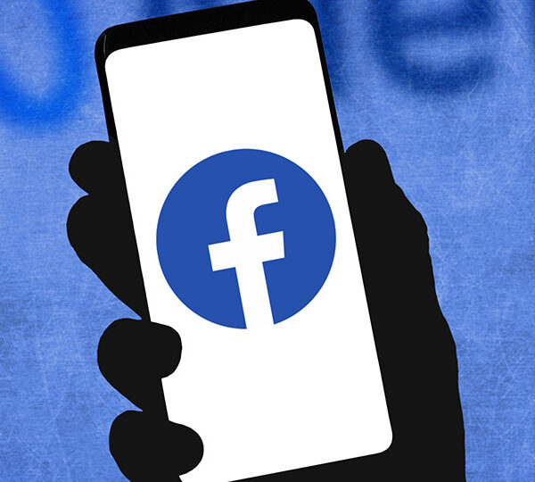 Eine Person hat ein Smartphone in der Hand, wo das Facebook-Logo zu sehen ist.