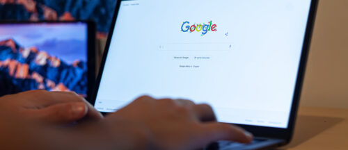 Bildbeschreibung: Das Bild zeigt eine Person, die einen Laptop benutzt, um die Google-Homepage anzuzeigen.
