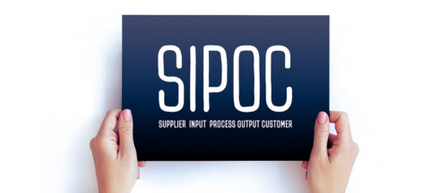 Zwei Hände halten ein Schild mit der Aufschrift "SIPOC" und dem Text "Supplier, Input, Process, Output, Customer".